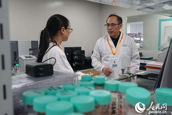 徐剛博士在實(shí)驗(yàn)室與工作人員交流。人民網(wǎng)記者 郝帥攝